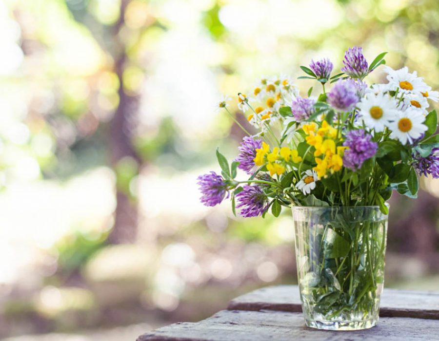 Bouquet of wildflowers on the wood table in the blurred nature background