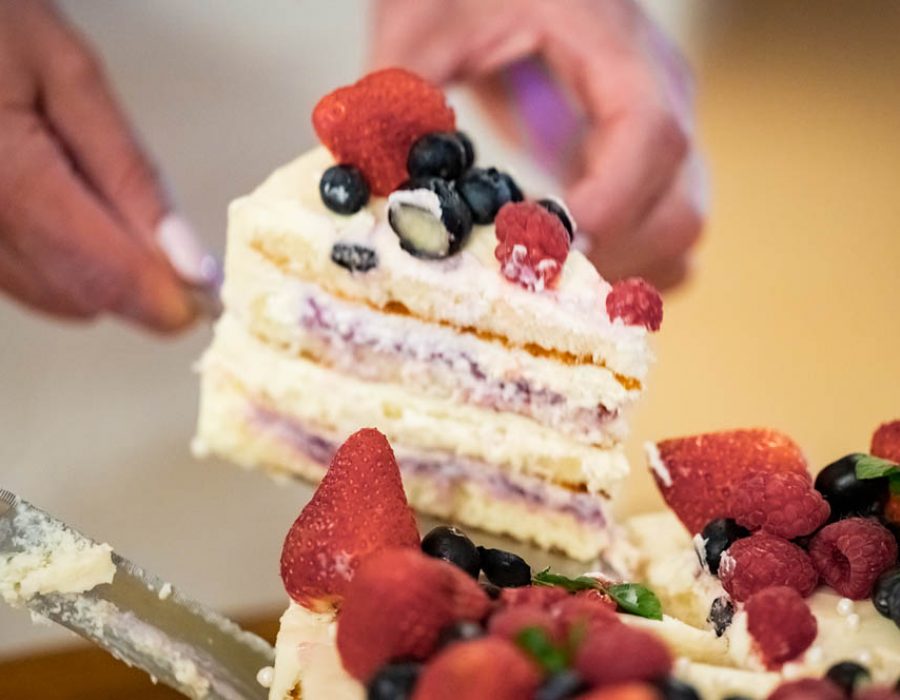 woman cuts a birthday cake with fruits and berries close-up